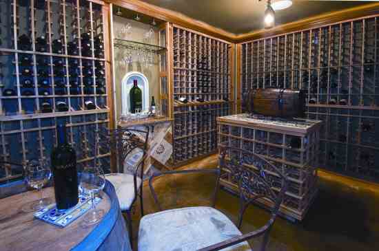 In this wine cellar, the homeowners used green seal-certified, low-VOC paint, wine racks made from salvaged wood, light fixture covered with recycled wine bottle, cabinet fashioned from wine crates, and radiant in-floor heat to eliminate forced-air dust.